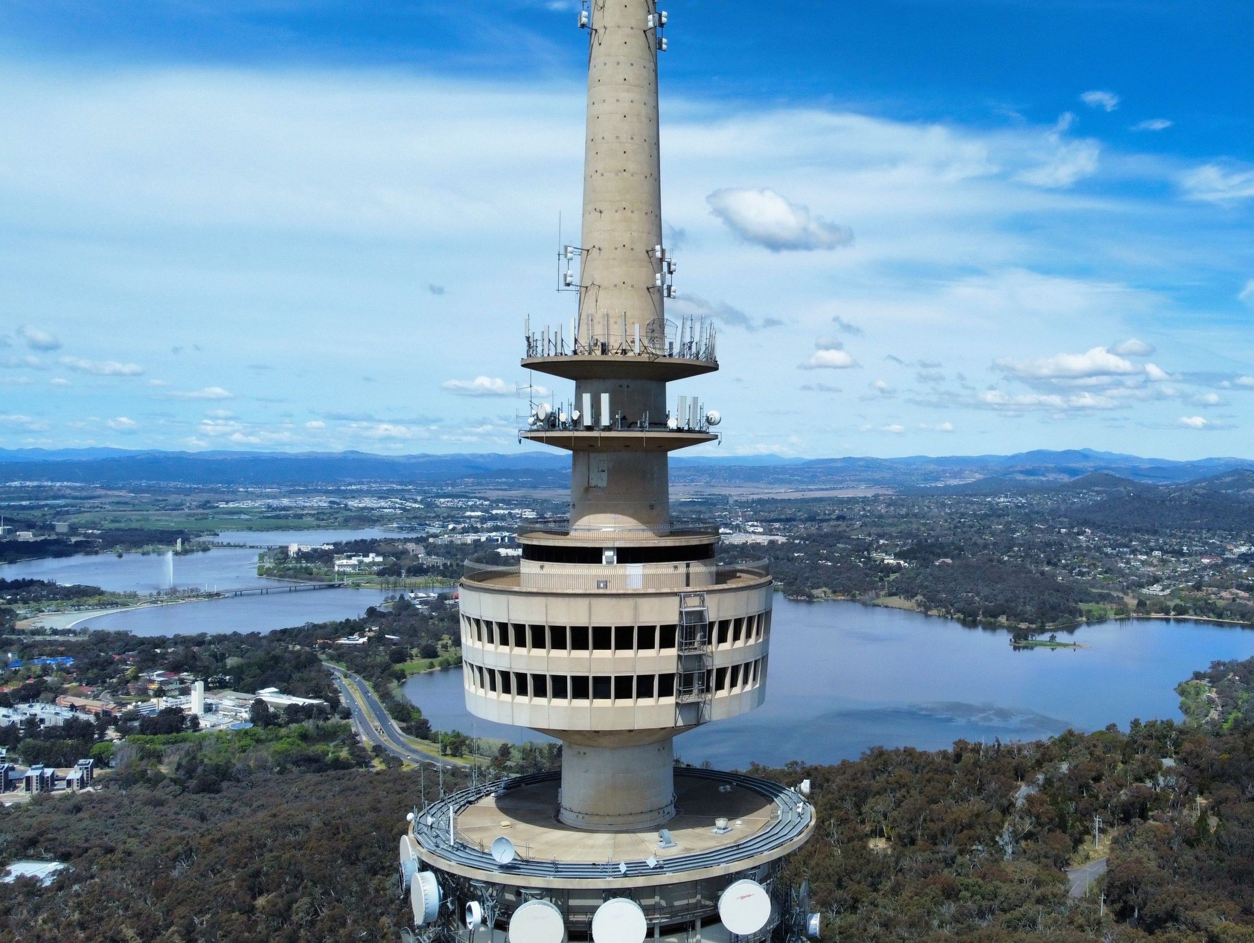 An aerial view of Telstra Tower with lake and city view background